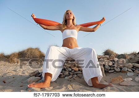 Stock Image - Healthy young woman meditating on the beach. Fotosearch