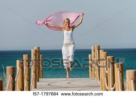 Healthy young woman skipping down a boardwalk View Large Photo Image Picture - Healthy young woman skipping down a boardwalk. Fotosearch