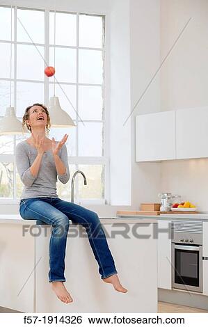 Stock Photograph - Healthy young woman throwing an apple into the air. Fotosearch