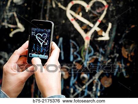 Heart with arrow painted on a wall and close-up of female hands with a phone making a photo in the Medina of Fez, Morocco, Africa View Large Photo Image Stock Photograph - Heart with arrow painted on a wall and close-up of female hands with a phone making a photo in the Medina of Fez, Morocco, Africa. Fotosearch