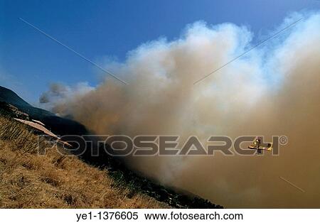 Heavy smoke from a forest fire travels towards and threatens a house with rescue plane visible in the sky, Propriano, Corsica, France View Large Photo Image Stock Photography - Heavy smoke from a forest fire travels towards and threatens a house with rescue plane visible in the sky, Propriano, Corsica, France. Fotosearch