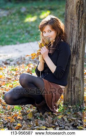 Hiding behind a bunch of fallen Autumn leaves pretty young woman View Large Photo Image Stock Photo - Hiding behind a bunch of fallen Autumn leaves pretty young woman. Fotosearch