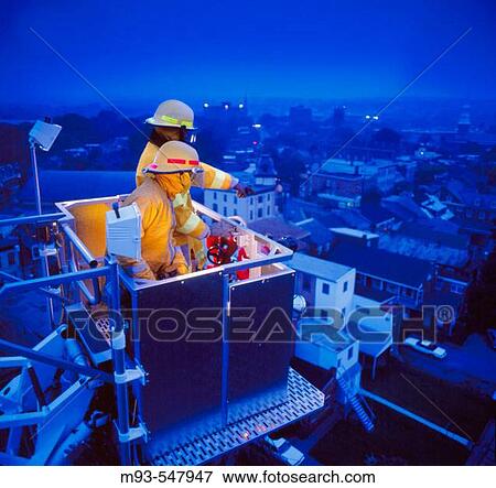 High angle view of two firemen in a high-reach apparatus, overlooking a city at dusk View Large Photo Image Stock Photo - High angle view of two firemen in a high-reach apparatus, overlooking a city at dusk. Fotosearch