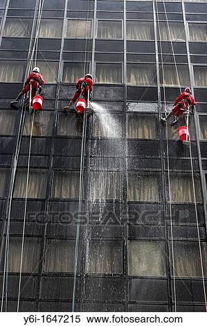 Stock Photography - High rise window cleaners work suspended on ropes Orchard Road Singapore. Fotosearch