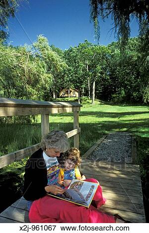 Highland, Michigan - Susan Newell reads to her daughter, Mariel West, 4, outside the Bass Lake cabin in Highland State Recreation Area MR View Large Photo Image Stock Photo - Highland, Michigan - Susan Newell reads to her daughter, Mariel West, 4, outside the Bass Lake cabin in Highland State Recreation Area MR. Fotosearch