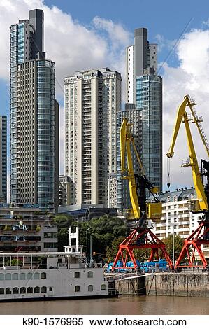 Highrise residential apartment buildings at the waterfront of the harbor, docklands, at a sunny day, blue sky, with a crane in the foreground, Buenos Aires, Argentina, South America View Large Photo Image Stock Photography - Highrise residential apartment buildings at the waterfront of the harbor, docklands, at a sunny day, blue sky, with a crane in the foreground, Buenos Aires, Argentina, South America. Fotosearch