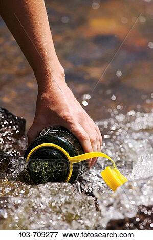 Hiker filling a water bottle in a mountain stream, San Juan Mountains, Colorado, USA View Large Photo Image Stock Photo - Hiker filling a water bottle in a mountain stream, San Juan Mountains, Colorado, USA. Fotosearch