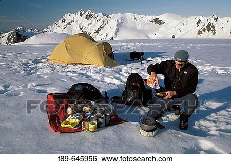 Stock Photograph - Hiker fixing breackfast in front of the tent, Denali Narional Park. Alaska, USA. Fotosearch