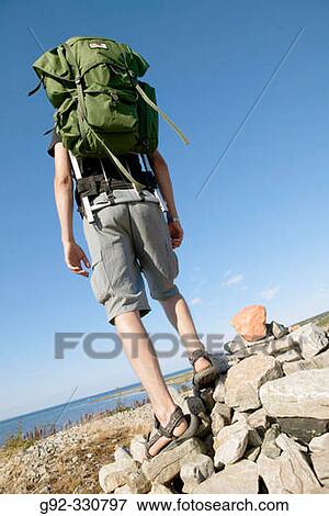 Hiker on pile of stones, with guiding sign. Sk? ne. Sweden View Large Photo Image Stock Photo - Hiker on pile of stones, with guiding sign. Sk? ne. Sweden. Fotosearch