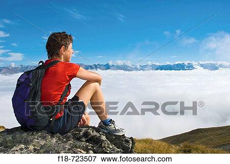 Stock Photo - Hiker rests on the peak of Ben Ohau, Southern Alps, New Zealand. Fotosearch