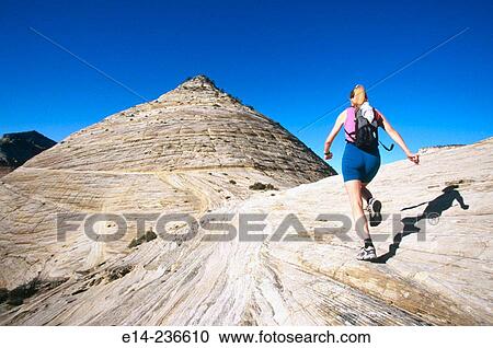 Stock Image - Hiker running on slick rock at Zion National Park. Utah. USA. Fotosearch