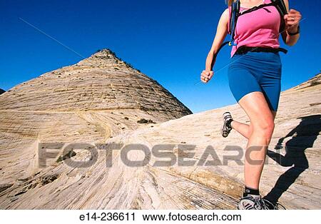 Stock Image - Hiker running on slick rock at Zion National Park. Utah. USA. Fotosearch