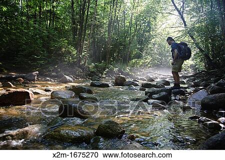 Hiker standing on rock in morning fog along Cedar Brook during the summer months in the Pemigewasset Wilderness of Lincoln, New Hampshire USA View Large Photo Image Stock Image - Hiker standing on rock in morning fog along Cedar Brook during the summer months in the Pemigewasset Wilderness of Lincoln, New Hampshire USA. Fotosearch
