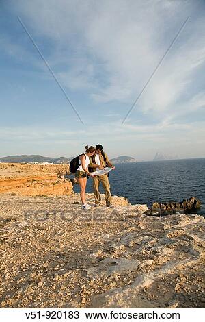 Stock Image - Hikers consulting the map in the cliff. Fotosearch