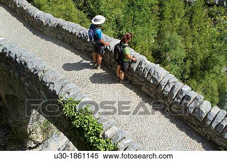 Hikers walking on San Urbez Bridge above Bell's river, in Aisclo Valley, canyon belonging to Ordesa y Monte Perdido National Park Pyrenees Fanlo Huesca province Arag? n Spain View Large Photo Image Stock Photography - Hikers walking on San Urbez Bridge above Bell's river, in Aisclo Valley, canyon belonging to Ordesa y Monte Perdido National Park Pyrenees Fanlo Huesca province Arag? n Spain. Fotosearch