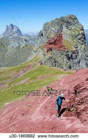 Stock Image - Hikers walking to summit of Anayet, an old volcano in Tena valley, and view of Midi d? Ossau Peak France Formigal Sallent de GBllego Pyrenees Huesca province Arag? n Spain. Fotosearch