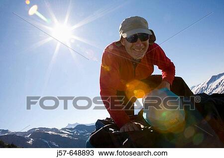 Stock Image - Hiking and climbing in Glacier Peak Wilderness. Washington USA. Packing a pack looking for lunch on the hike out.. Fotosearch