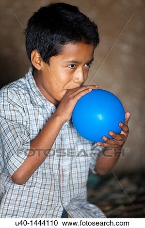 Stock Image - Hispanic boy blowing up balloon. Fotosearch
