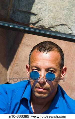 Stock Photography - Hispanic man posing in blue colored sunglasses.. Fotosearch