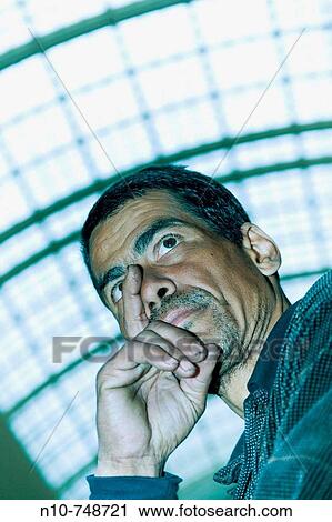 Stock Image - Hispanic man standing under an office building skylight.. Fotosearch