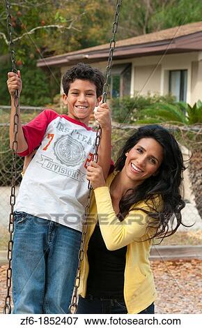 Hispanic single mother and som age 11 on swing in park at playground near home outdoors View Large Photo Image Stock Photo - Hispanic single mother and som age 11 on swing in park at playground near home outdoors. Fotosearch