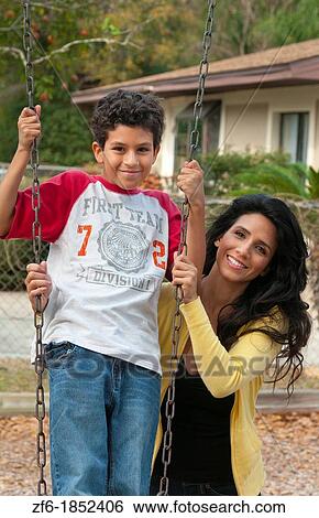 Hispanic single mother and som age 11 on swing in park at playground near home outdoors View Large Photo Image Stock Photograph - Hispanic single mother and som age 11 on swing in park at playground near home outdoors. Fotosearch