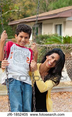 Hispanic single mother and som age 11 on swing in park at playground near home outdoors View Large Photo Image Stock Photography - Hispanic single mother and som age 11 on swing in park at playground near home outdoors. Fotosearch