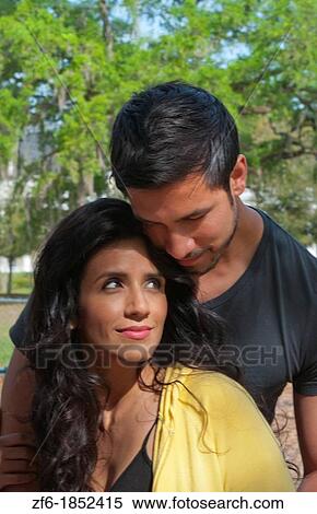 Stock Photography - Hispanic Spanish couple in romance situation in park outdoors portrait with holding and love. Fotosearch