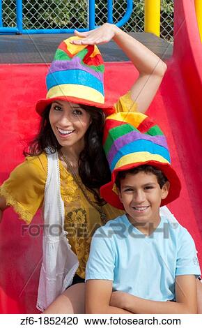 Hispanic spanish mom and son with colorful hats in playground park outdoors on colorful slide View Large Photo Image Stock Image - Hispanic spanish mom and son with colorful hats in playground park outdoors on colorful slide. Fotosearch