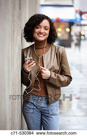 Hispanic woman listening to her Ipod on street View Large Photo Image Picture - Hispanic woman listening to her Ipod on street. Fotosearch