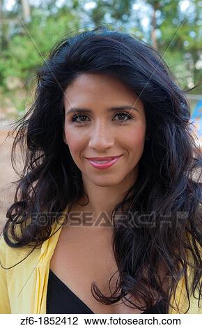 Stock Image - Hispanic woman spanish portrait with black hair and sexy outfit outdoor portait and yellow outfit. Fotosearch