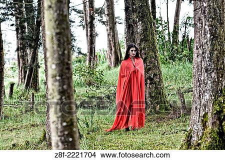 Hispanic woman with a red cloak, recreating a modern fairy tale of Little Red Riding Hood. View Large Photo Image Picture - Hispanic woman with a red cloak, recreating a modern fairy tale of Little Red Riding Hood.. Fotosearch
