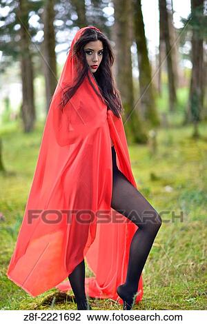 Stock Image - Hispanic woman with a red cloak, recreating a modern fairy tale of Little Red Riding Hood.. Fotosearch