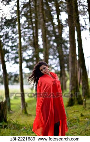 Stock Photo - Hispanic woman with a red cloak, recreating a modern fairy tale of Little Red Riding Hood.. Fotosearch