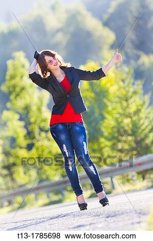 Stock Photo - Hitchhiking on a country-road young woman. Fotosearch