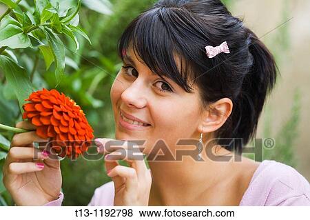 Holding a Red flower in a park young woman is smiling at camera View Large Photo Image Stock Photo - Holding a Red flower in a park young woman is smiling at camera. Fotosearch