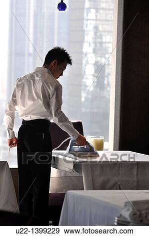 Stock Photo - Hong Kong: an employee ironing the tablecloths at a restaurant of the Mandarin Oriental Hong Kong Hotel. Fotosearch