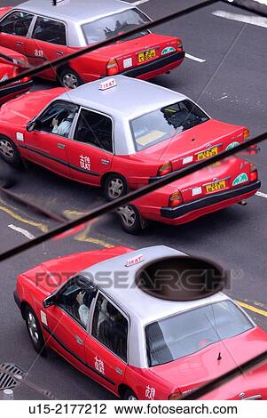 Stock Image - Hong Kong, China, Asia. Mirror image of typical red and silver Hong Kong Taxis.. Fotosearch