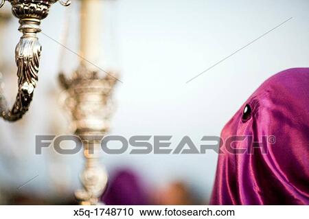 Stock Image - Hooded penitent behind a float, Holy Week, Seville, Spain. Fotosearch