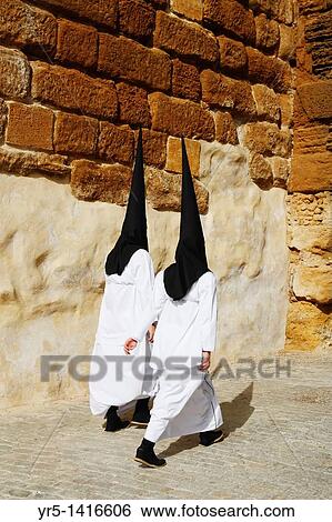 Stock Photograph - Hooded penitents near church during Semana Santa in Carmona near Seville, Andalusia, Spain. Fotosearch