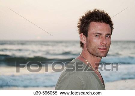 Horizontal shot of a good-looking man in a green t-shirt next to the Indian ocean with the sun setting. View Large Photo Image Stock Photography - Horizontal shot of a good-looking man in a green t-shirt next to the Indian ocean with the sun setting.. Fotosearch