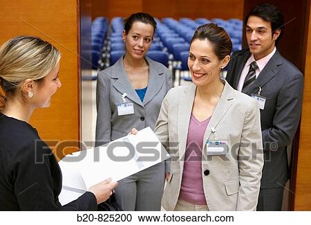 Stock Image - Hostess supplying documentation to conventioneers, convention center, Kursaal Center. San Sebastian, Guipuzcoa, Basque Country, Spain. Fotosearch