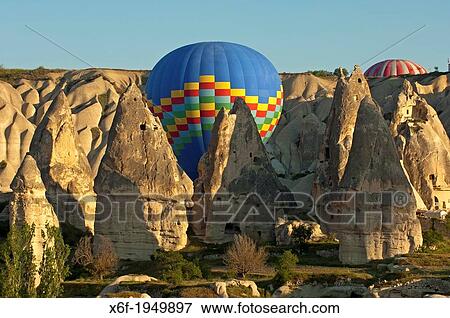 Hot air balloon manoeuvres between tuff rock cones in the rock sites of Cappadocia, Goreme, Turkey. View Large Photo Image Stock Photo - Hot air balloon manoeuvres between tuff rock cones in the rock sites of Cappadocia, Goreme, Turkey.. Fotosearch
