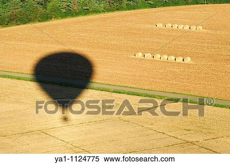 Stock Photography - Hot air balloon shadow over harvesting wheat field. Meuse, Lorraine region, France. Fotosearch