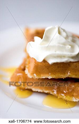 Hot, fresh waffles drizzled with syrup and topped with whipped cream View Large Photo Image Picture - Hot, fresh waffles drizzled with syrup and topped with whipped cream. Fotosearch