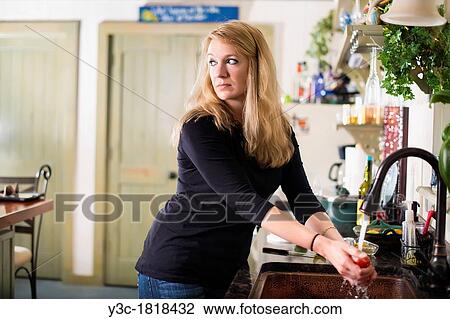 Housewife, 35, caucasian, looking suspicious while washing vegetable in her kitchen sink View Large Photo Image Stock Image - Housewife, 35, caucasian, looking suspicious while washing vegetable in her kitchen sink. Fotosearch