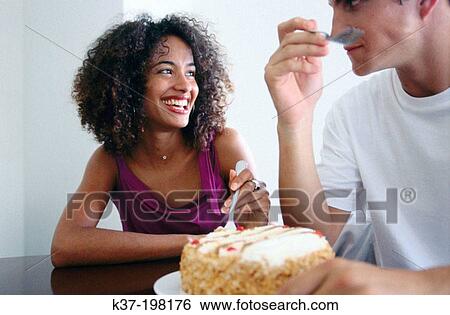 Stock Photograph - Hugry couple eating cake with fridge. Fotosearch