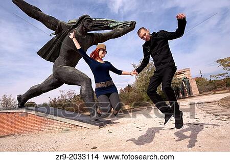 Hungarian man and woman jumping in front of monument while visiting Memento Statue Park in Budapest, Hungary. View Large Photo Image Picture - Hungarian man and woman jumping in front of monument while visiting Memento Statue Park in Budapest, Hungary.. Fotosearch