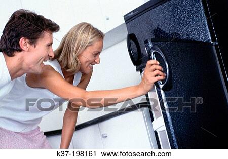 Stock Image - Hungry couple looking in fridge. Fotosearch