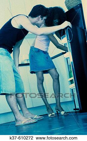 Stock Image - Hungry young couple looking in fridge. Fotosearch